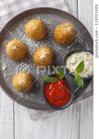 Arancini with cheese and pepper served with two sauces close-up in a plate. Vertical top view 119301489
