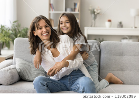 Happy laughing young mom little daughter playing tickling on couch 119302099