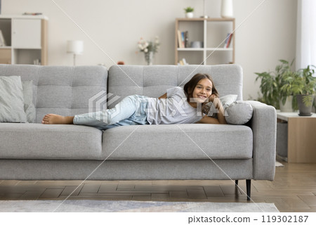 Portrait cheerful preteen girl lying on sofa in comfortable pose Portrait cheerful preteen girl lying on sofa in comfortable pose 119302187