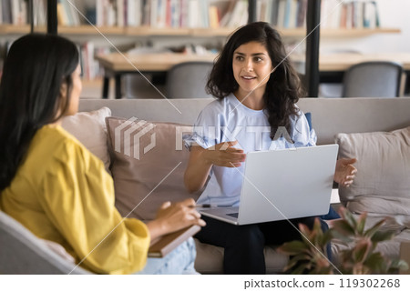 Positive engaged young Indian project manager talking to female colleague Positive engaged young Indian project manager talking to female colleague 119302268