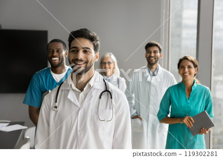 Happy young male doctor posing in front of friendly colleagues Happy young male doctor posing in front of friendly colleagues 119302281