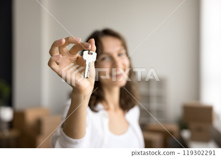 Blurred portrait happy young lady realtor show keys at camera Blurred portrait happy young lady realtor show keys at camera 119302291