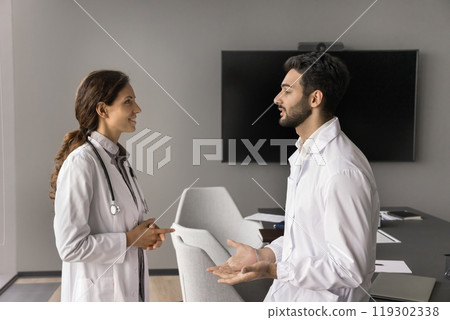 Two doctors colleagues hold professional conversation at healthcare center boardroom 119302338