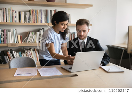 Diverse business colleagues working on marketing strategy at laptop together Diverse business colleagues working on marketing strategy at laptop together 119302347