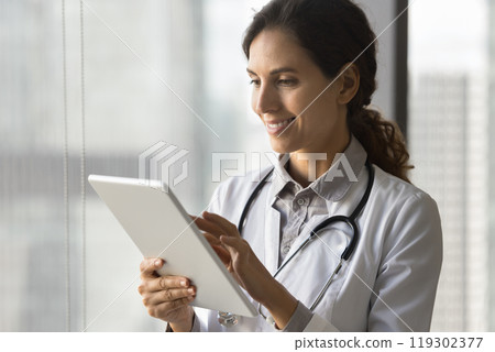 Confident female doctor type history case on tablet pc Confident female doctor type history case on tablet pc 119302377