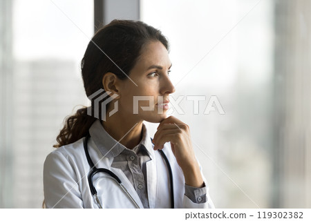 Pensive millennial woman doctor look away ponder on difficult case 119302382