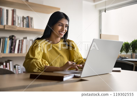 Cheerful successful young Indian project manager woman enjoying online communication Cheerful successful young Indian project manager woman enjoying online communication 119302555