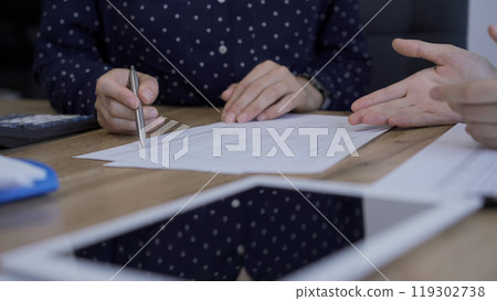 Accountants or auditors are discussing review of financial documents while sitting at the wooden desk in office. Professionals analyzing paper reports and using calculator and tablet computer, close Accountants or auditors are discussing review of financial documents while sitting at the wooden desk in office. Professionals analyzing paper reports and using calculator and tablet computer, close 119302738