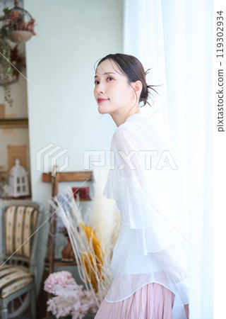 A woman surrounded by lace curtains 119302934