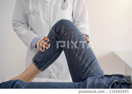 Doctor and patient are at the medical inspection in clinic. Orthopedic examines the knee of a young woman. Medicine concept 119302955