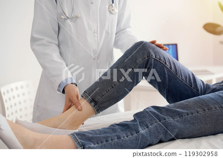 Doctor and patient are at the medical inspection in clinic. Orthopedic examines the knee of a young woman. Medicine concept 119302958