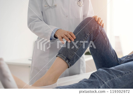 Doctor and patient are at the medical inspection in clinic. Orthopedic examines the knee of a young woman. Medicine concept Doctor and patient are at the medical inspection in clinic. Orthopedic examines the knee of a young woman. Medicine concept 119302972