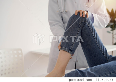 Doctor and patient are at the medical inspection in clinic. Orthopedic examines the knee of a young woman. Medicine concept Doctor and patient are at the medical inspection in clinic. Orthopedic examines the knee of a young woman. Medicine concept 119302973