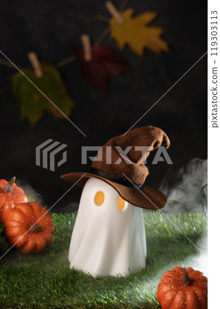 Halloween ghost wearing a witch's hat with glowing eyes surrounded by pumpkins and autumn leaves in fog. Background for your text. 119303113