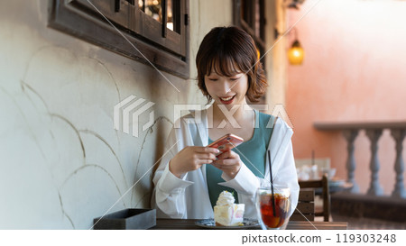 Woman taking a photo of a cake at a cafe 119303248