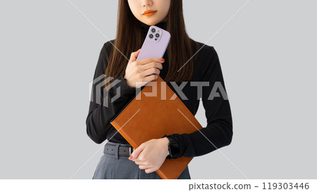 Woman/businesswoman holding a smartphone and a binder 119303446