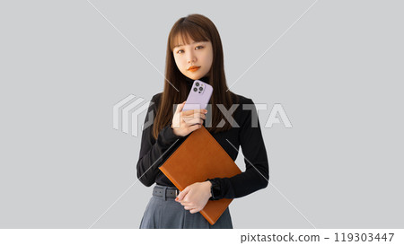 Woman/businesswoman holding a smartphone and a binder 119303447