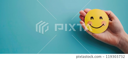 An individual proudly holds a yellow egg with a smiling face design 119303732