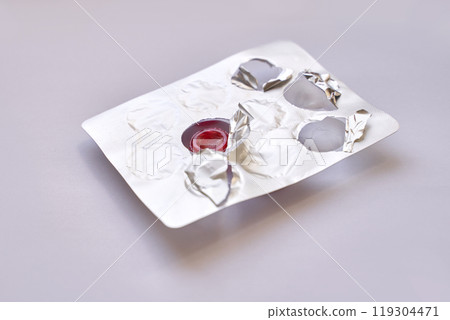 Open blister pack with one remaining red pill on light background highlighting 119304471