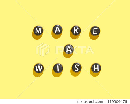 Motivational message make a wish with black letter beads on bright yellow Motivational message make a wish with black letter beads on bright yellow 119304476