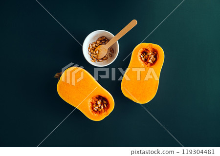 Halved butternut squash and roasted seeds in a bowl, highlighting a DIY roasted seeds snack recipe 119304481