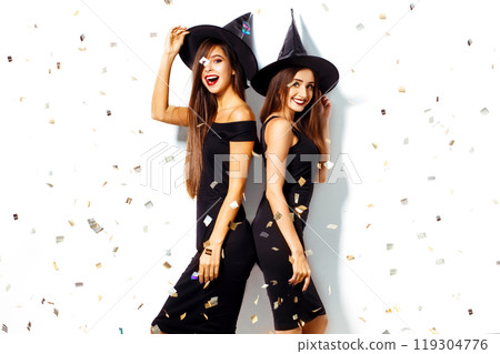 nice portrait of two beautiful young woman in black witch halloween costumes on party over white background. nice portrait of two beautiful young woman in black witch halloween costumes on party over white background. 119304776