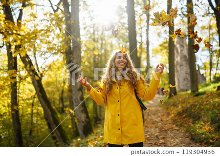 Woman in a yellow coat with backpack walks along wooden staircase, enjoying autumn scenery in forest Woman in a yellow coat with backpack walks along wooden staircase, enjoying autumn scenery in forest 119304936