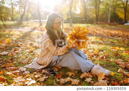 Young woman taking pictures in the autumn forest. Lady Walking In Fall Park With Yellow Foliage. 119305059