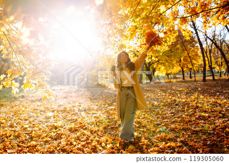 Young woman taking pictures in the autumn forest. Lady Walking In Fall Park With Yellow Foliage. 119305060