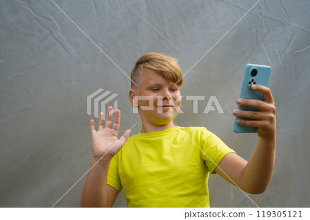 An attractive boy makes a video call on the phone An attractive boy makes a video call on the phone 119305121