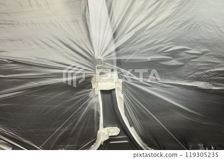 The automobile is covered in protective plastic for proper storage and safety measures The automobile is covered in protective plastic for proper storage and safety measures 119305235
