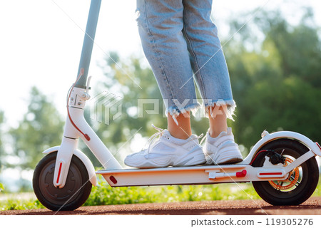 Legs of woman riding electric kick scooter on urban outdoor. Ecological transportation concept. 119305276