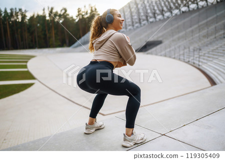 Sports woman in sportswear does exercises outdoors. . Sport, active lifestyle, healthy lifestyle concept. 119305409
