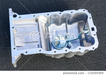 Passenger car engine new aluminum oil sump with oil receiver tube on gray background, new crankcase Passenger car engine new aluminum oil sump with oil receiver tube on gray background, new crankcase 119305944