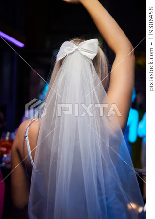 An Elegant Bride in a beautiful Veil and Bow, enjoying a vibrant Nightclub with friends An Elegant Bride in a beautiful Veil and Bow, enjoying a vibrant Nightclub with friends 119306458