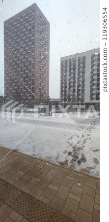 Snowfall blankets urban landscape outside residential buildings during winter morning Snowfall blankets urban landscape outside residential buildings during winter morning 119306554