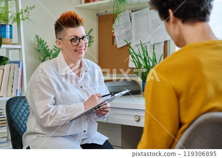 Female psychologist with clipboard working with young male patient in office 119306895