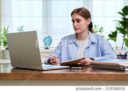 Teenage girl student studying online sitting at home at desk using laptop for video conference Teenage girl student studying online sitting at home at desk using laptop for video conference 119306910
