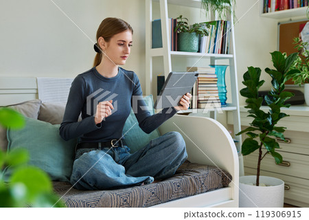 Teenage female student at home looking talking in web camera of digital tablet 119306915