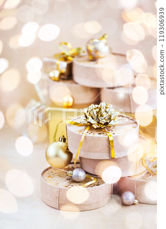 Christmas or New year round kraft gift boxes, gold holiday balls on a bokeh background of twinkling party lights of garland Christmas or New year round kraft gift boxes, gold holiday balls on a bokeh background of twinkling party lights of garland 119306939