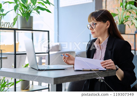 Middle aged businesswoman having video conference on laptop sitting at desk Middle aged businesswoman having video conference on laptop sitting at desk 119307349