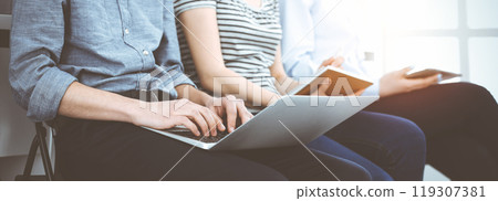 Group of casual dressed business people working at meeting or conference in sunny office, close-up of hands. Businessman using tablet computer Group of casual dressed business people working at meeting or conference in sunny office, close-up of hands. Businessman using tablet computer 119307381