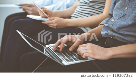 Group of casual dressed business people working at meeting or conference, close-up of hands. Businessman using laptop computer. Teamwork or coaching concept Group of casual dressed business people working at meeting or conference, close-up of hands. Businessman using laptop computer. Teamwork or coaching concept 119307382