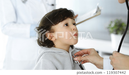 Woman-doctor examining a child patient by stethoscope. Cute arab toddler at physician appointment. Medicine concept Woman-doctor examining a child patient by stethoscope. Cute arab toddler at physician appointment. Medicine concept 119307442