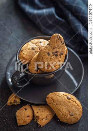 Biscotti frollini con gocce di cioccolato. Chocolate cookies in coffee cup on black table. Biscotti frollini con gocce di cioccolato. Chocolate cookies in coffee cup on black table. 119307449