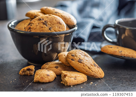 Biscotti frollini con gocce di cioccolato. Chocolate cookies on black table. Biscotti frollini con gocce di cioccolato. Chocolate cookies on black table. 119307453