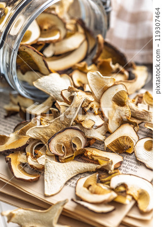 Dried porcini mushrooms. Sliced boletus in jar on white table. 119307464