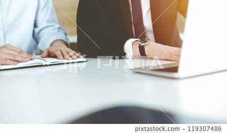 Unknown business people using laptop computer at the desk in modern office. Businessman or male entrepreneur is working with his colleague. Teamwork and partnership concept 119307486