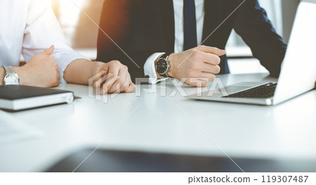 Unknown business people using laptop computer at the desk in modern office. Businessman or male entrepreneur is working with his colleague. Teamwork and partnership concept 119307487