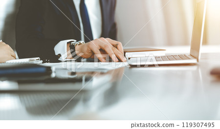 Unknown businessmen and woman sitting, working and discussing questions at meeting in sunny office, close-up. Success concept 119307495